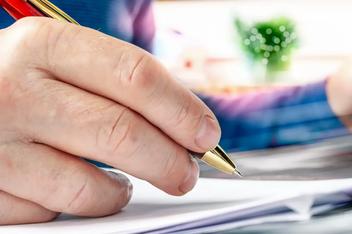 Hand unterschreibt Dokumente zur Bestattungsorganisation